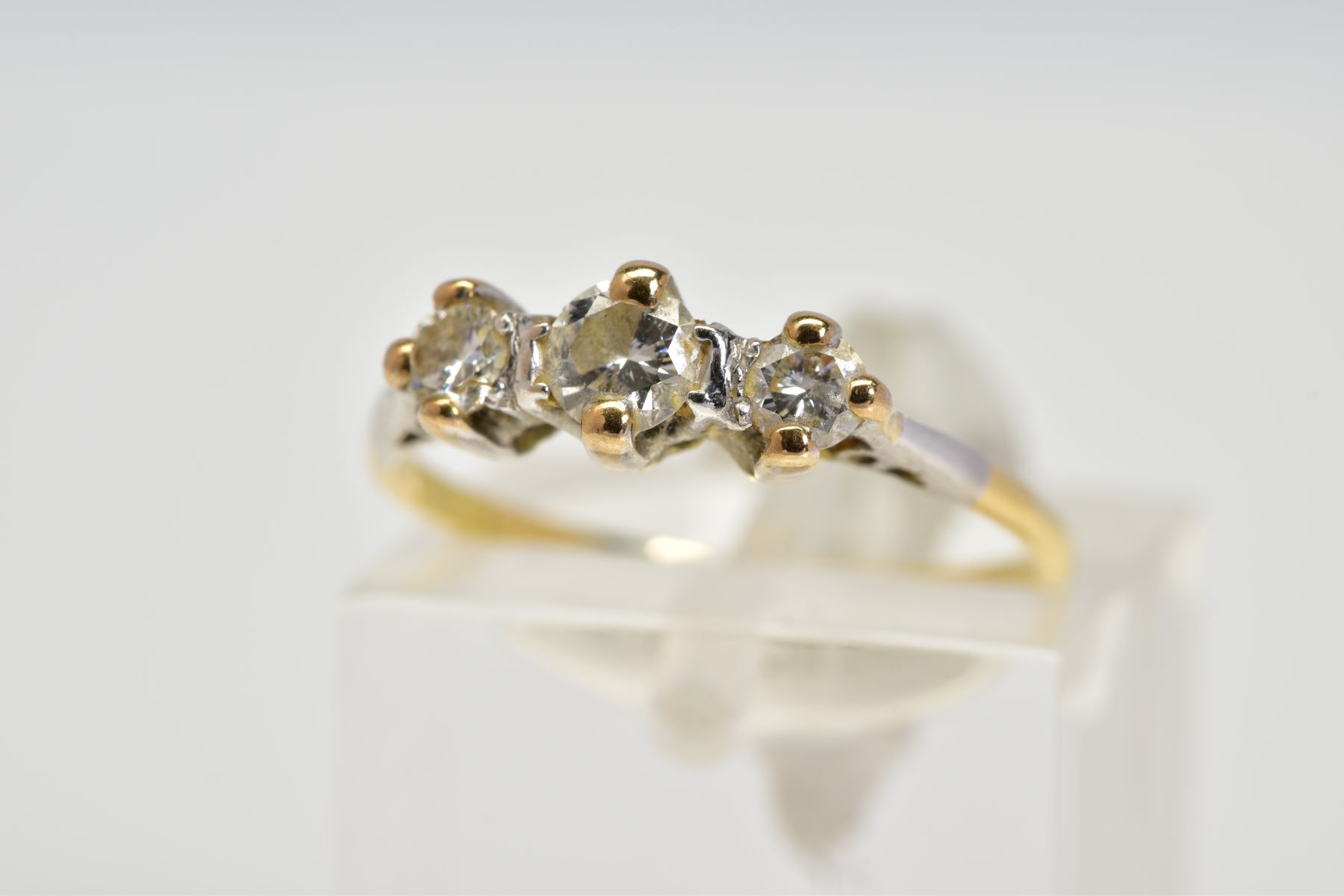 A YELLOW METAL THREE STONE DIAMOND RING, designed with three claw set, graduated round brilliant cut