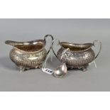 AN EDWARDIAN MATCHED SILVER CREAM JUG, of oval form and sugar bowl gadrooned rim, foliate scroll