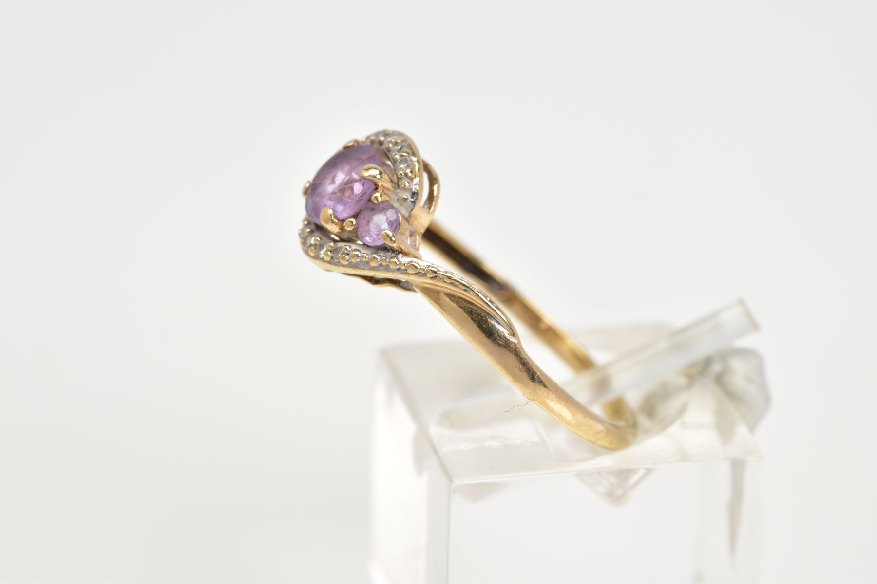 AN AMETHYST AND DIAMOND RING, the yellow metal ring of cross over design, set with three graduated - Image 2 of 3