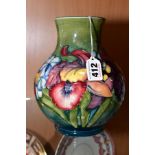 A MOORCROFT POTTERY BALUSTER VASE IN THE ORCHID AND SPRING FLOWERS PATTERN, on a green ground,