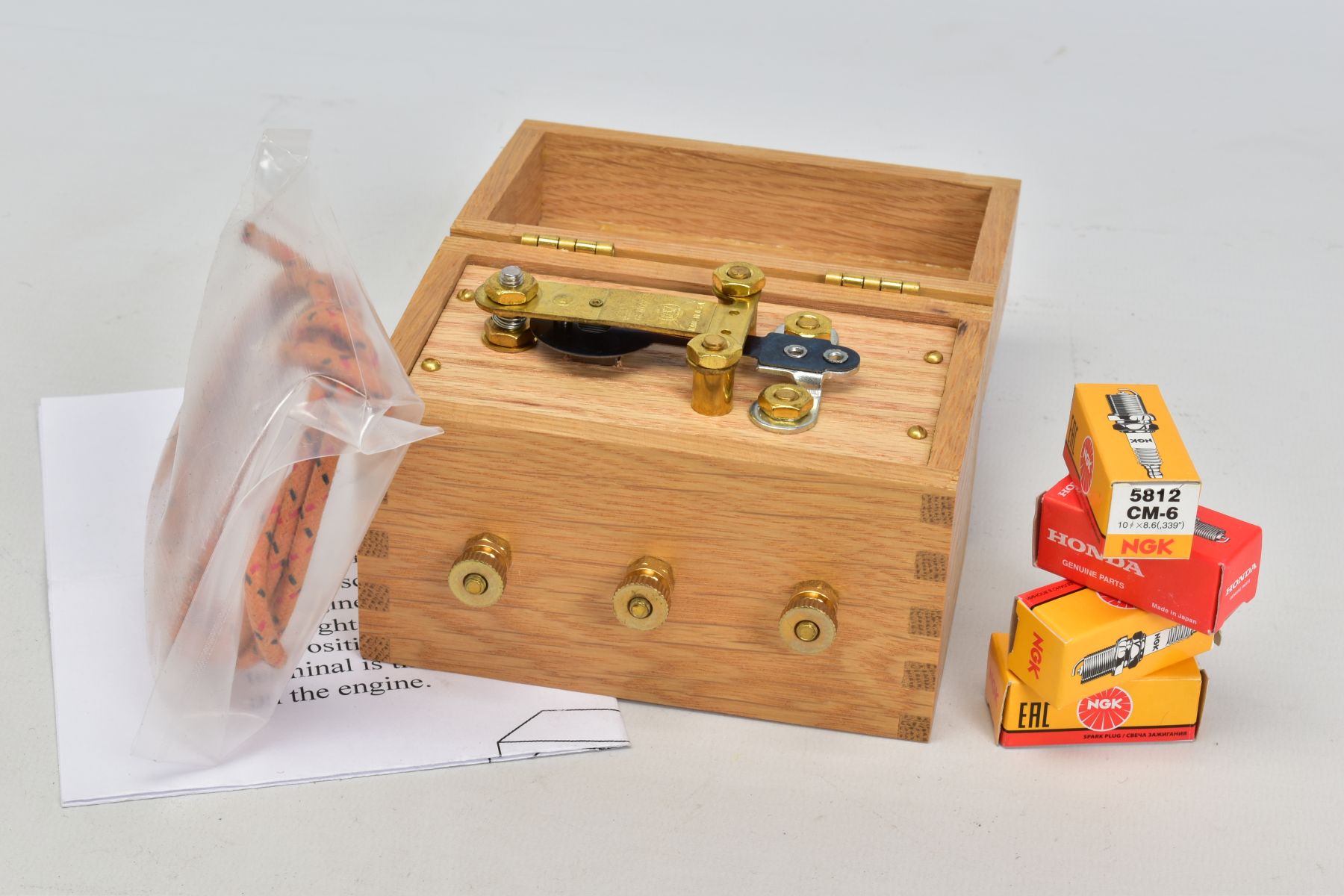 A RED WING MOTOR CO. OAK CASED COIL, a quantity of spark plug wire and four boxed spark plugs (3x