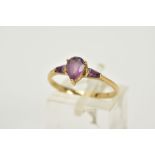 A 9CT GOLD AMETHYST RING, designed with a claw set pear cut amethyst, flanked with tapered cut