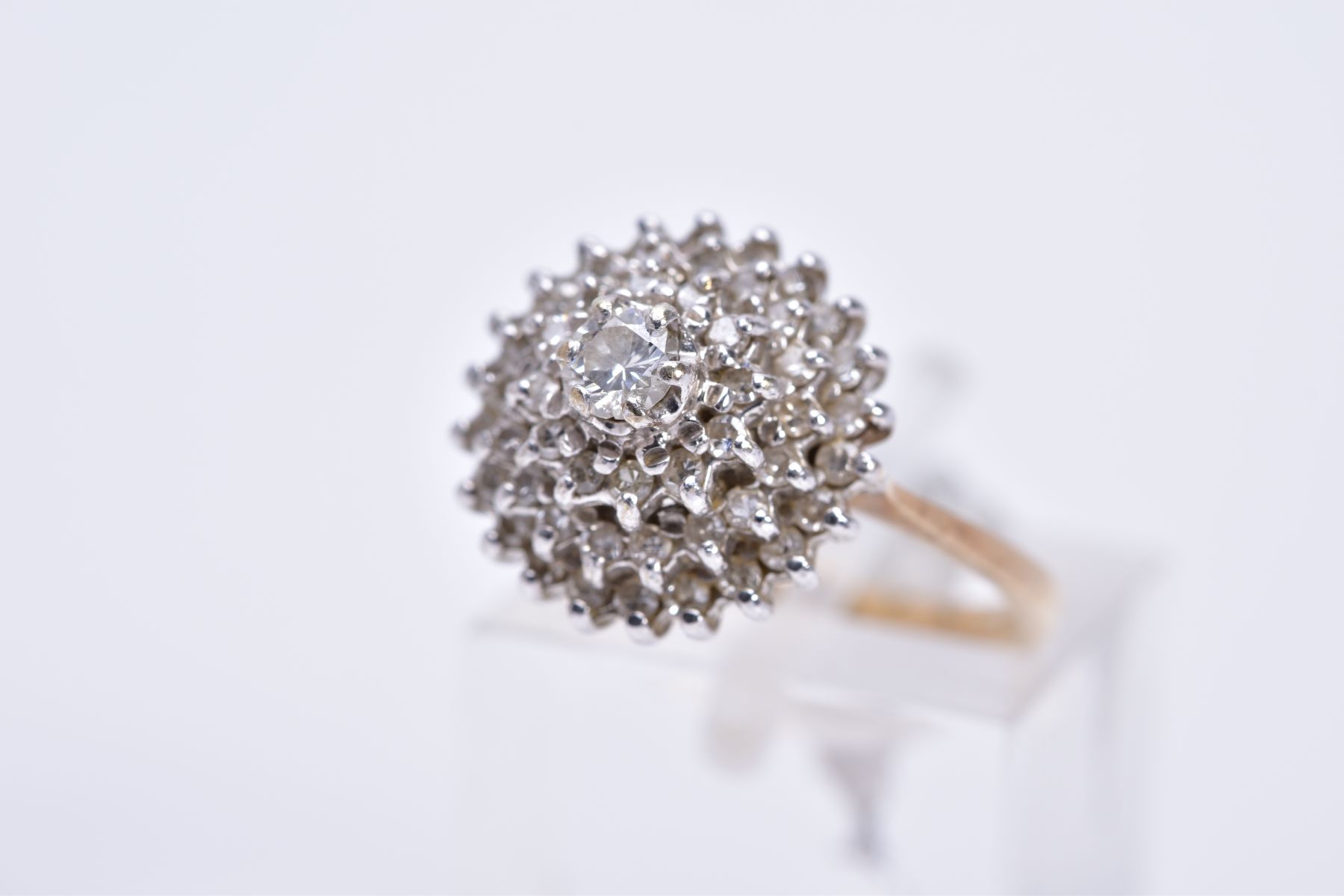 A 9CT GOLD DIAMOND CLUSTER RING, the tiered cluster with a central round brilliant cut diamond and