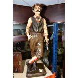 A PAINTED FIBRE GLASS MODEL OF A GOLFER, posed leaning on his golf club, square base, height 96cm