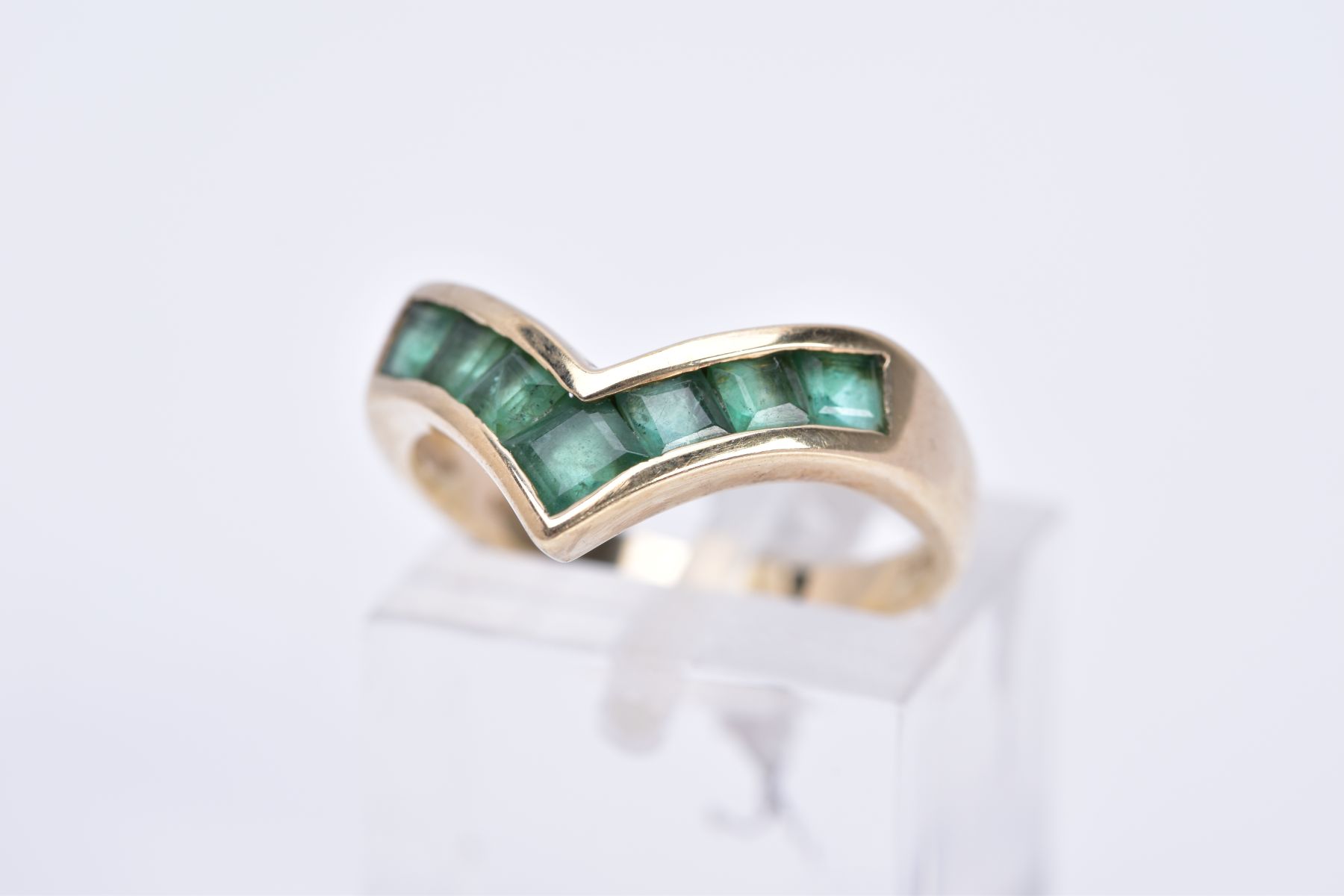 A 9CT GOLD EMERALD RING, of 'v' shape design set with square cut emeralds, plain polished band,