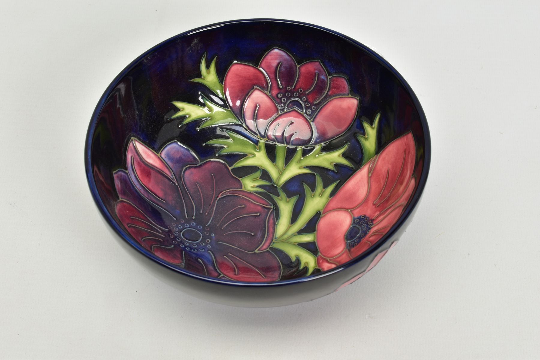 A MOORCROFT POTTERY FOOTED BOWL, 'Anemone' pattern on dark blue ground, impressed backstamp, No 34/