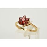 A 9CT GOLD GARNET CLUSTER RING, the tiered cluster set with seven circular cut garnets, tapered