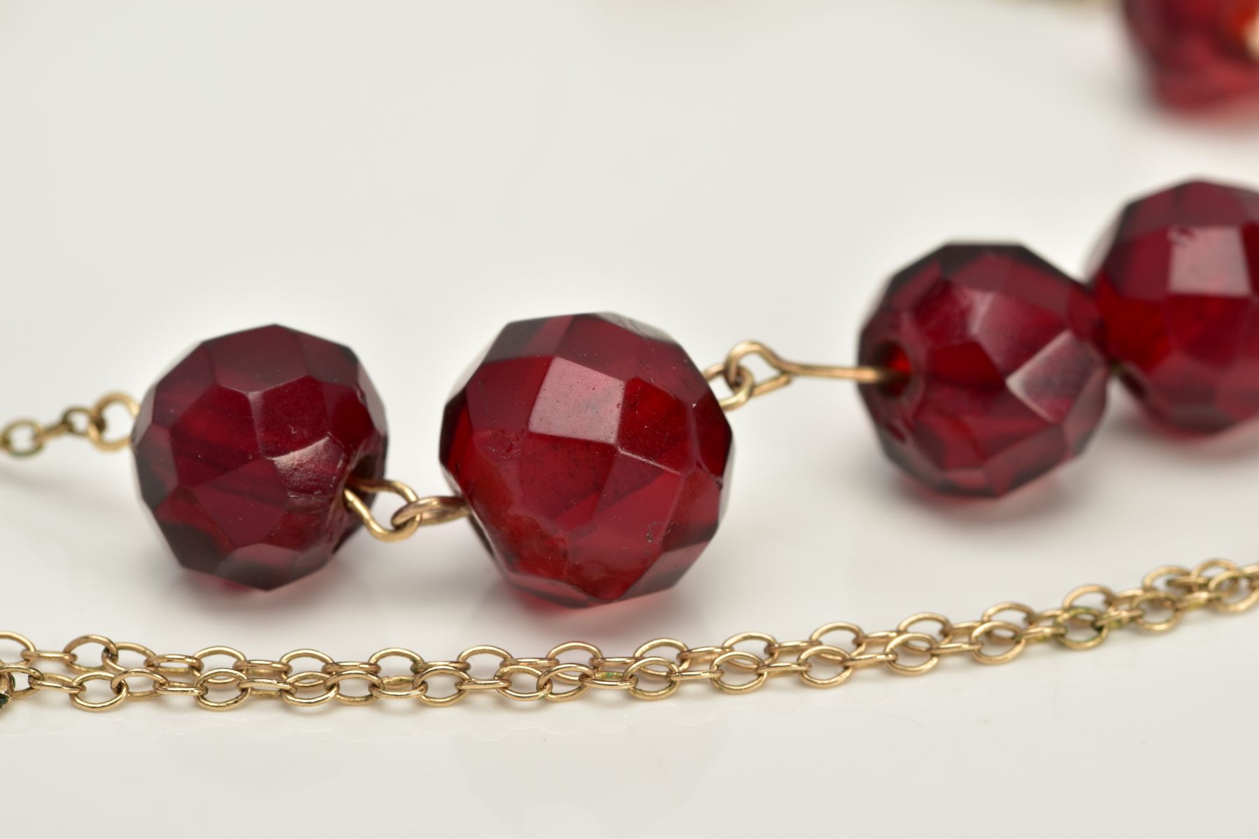 A YELLOW METAL BEADED NECKLACE, designed with a row of nine graduated faceted red beads, assessed as - Image 2 of 3