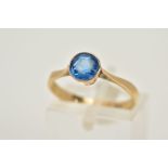 A YELLOW METAL GEM SET RING, set with a circular cut blue stone assessed as paste, tapered