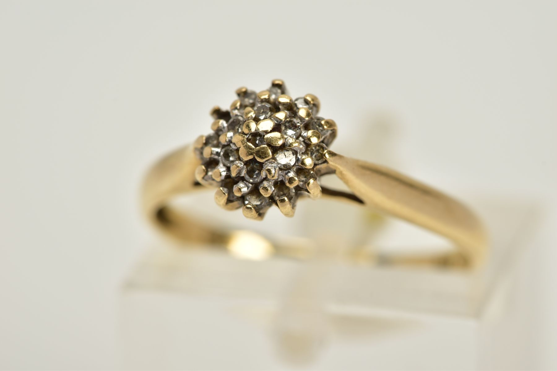 A YELLOW METAL DIAMOND CLUSTER RING, the tiered cluster set with single cut diamond, tapered