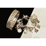 A SILVER BANGLE AND CHARM BRACELET, the silver hinged bangle, with engraved detailing all round