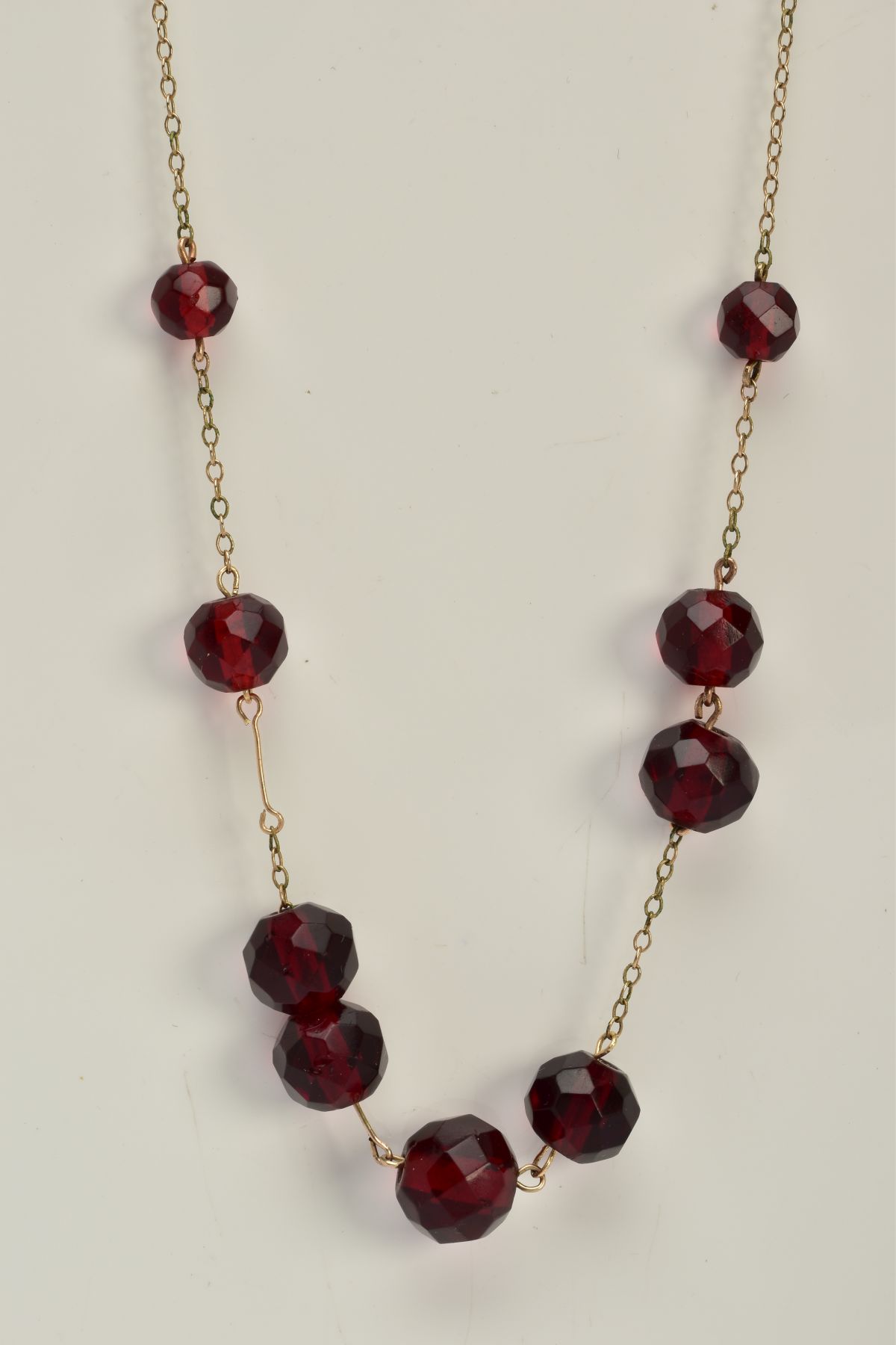 A YELLOW METAL BEADED NECKLACE, designed with a row of nine graduated faceted red beads, assessed as - Image 3 of 3