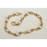 A YELLOW METAL QUARTZ AND DIAMOND LINE BRACELET, designed with nine oval cut colourless quartz,