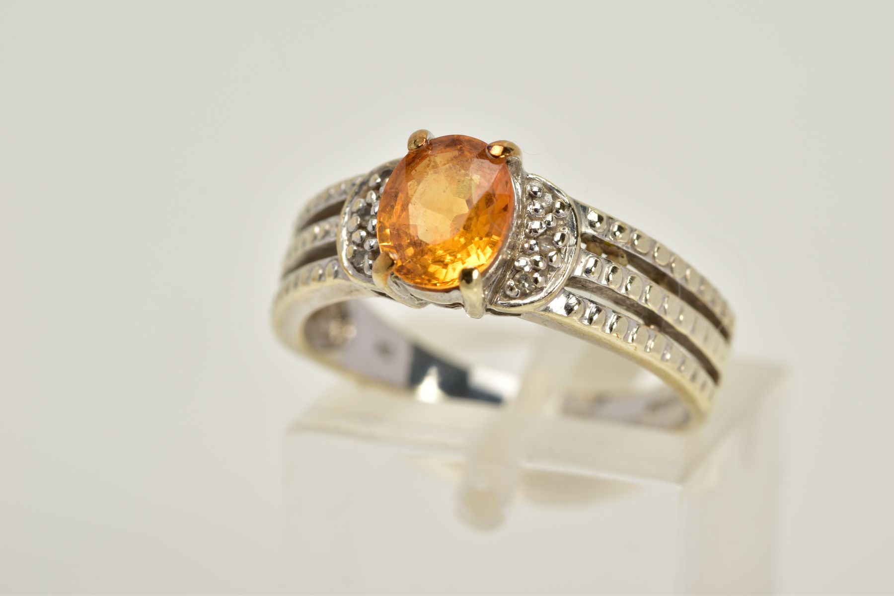 A 9CT WHITE GOLD YELLOW SAPPHIRE RING, designed with a claw set, oval cut yellow sapphire, flanked