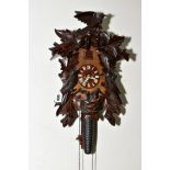 A 20TH CENTURY BLACK FOREST STYLE CUCKOO CLOCK, carved bird and leaf pediment and case sides, with