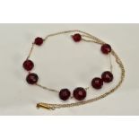 A YELLOW METAL BEADED NECKLACE, designed with a row of nine graduated faceted red beads, assessed as