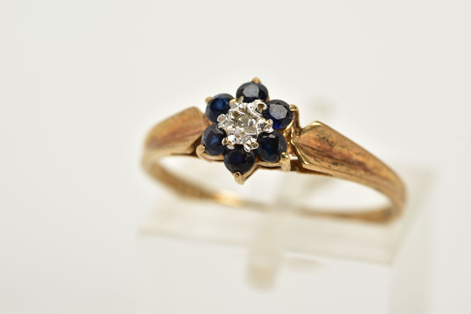 A 9CT GOLD SAPPHIRE AND DIAMOND CLUSTER RING, designed with a central single cut diamond, circular