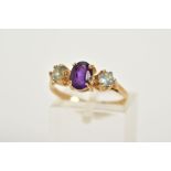 A 9CT GOLD AMETHYST AND TOPAZ RING, designed with a central claw set oval cut amethyst, flanked with