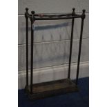 AN EARLY 20TH CENTURY RECTANGULAR TUBULAR BRASS STICK STAND, on a cast iron base with a removable