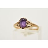 A 9CT GOLD AMETHYST RING, designed with a claw set oval cut amethyst, trifurcated shoulders,