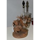 A BLACK FOREST CARVED WOOD LIQUEUR STAND, modelled as a bear carrying a bear cub in one hand and