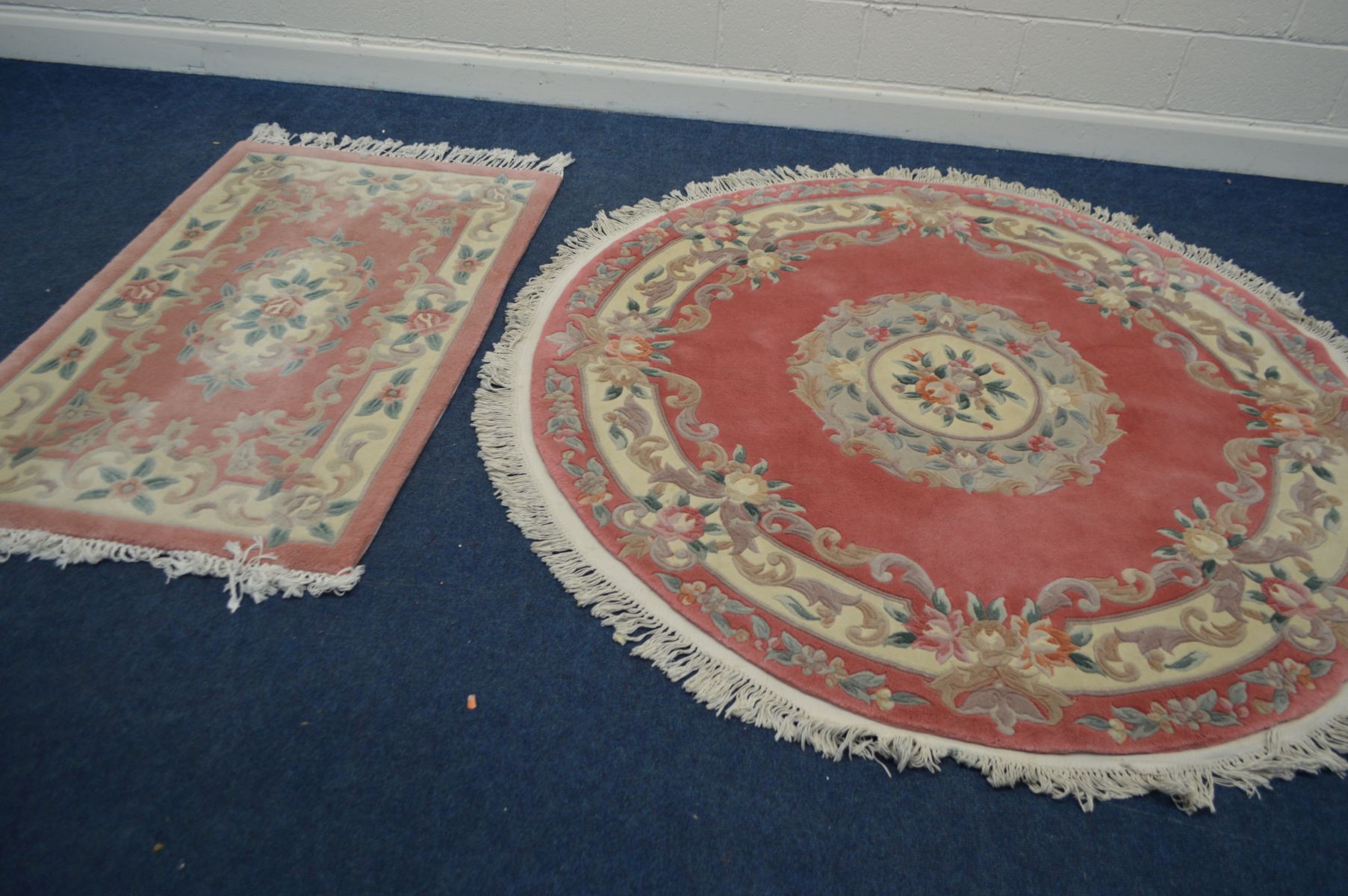 A CIRCULAR CHINESE PINK GROUND RUG, diameter 186cm, together with a similar rectangular rug (2)
