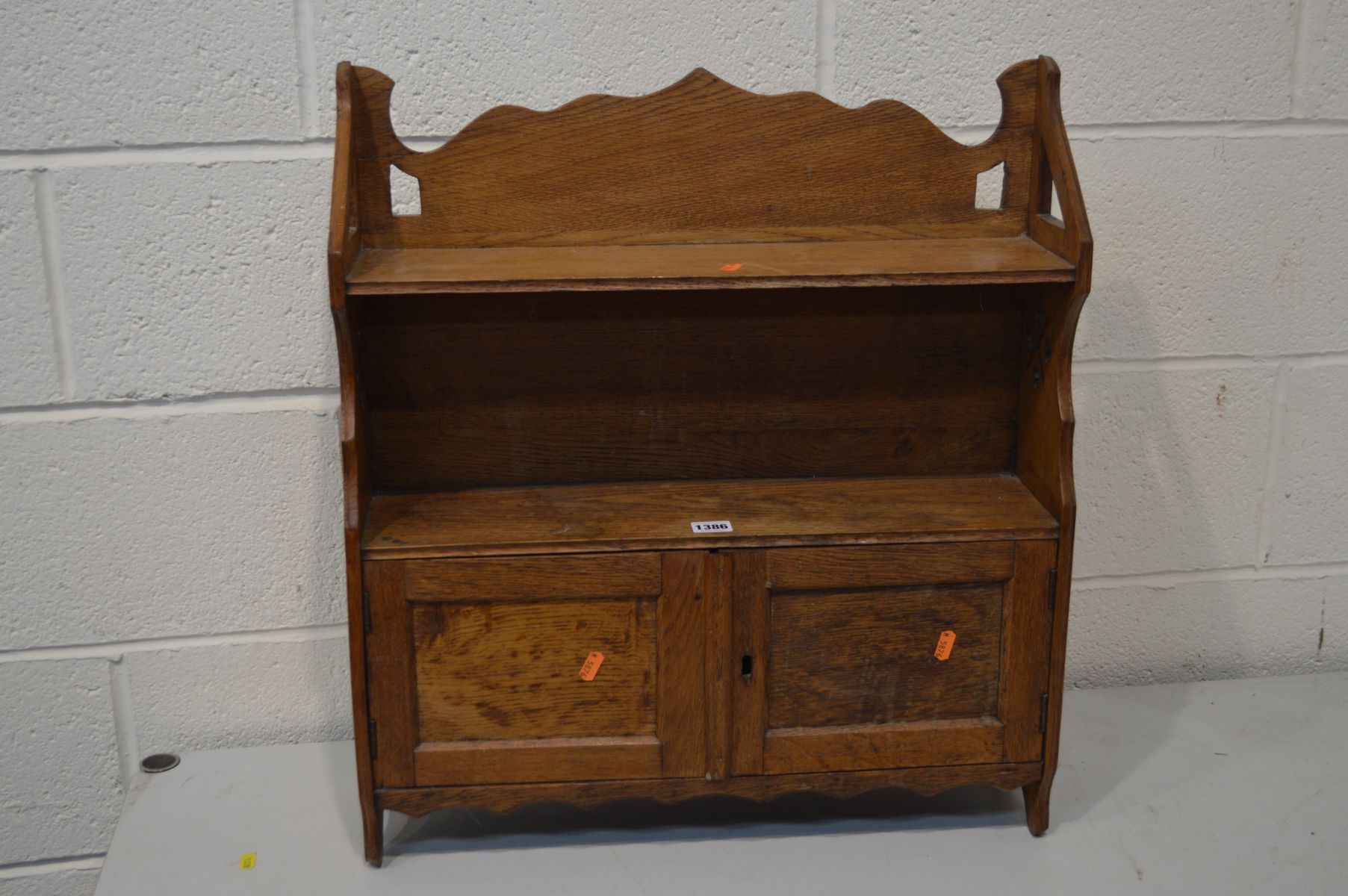 AN EARLY 20TH CENTURY OAK ARTS AND CRAFTS HANGING BOOKSHELF with a two door cupboard