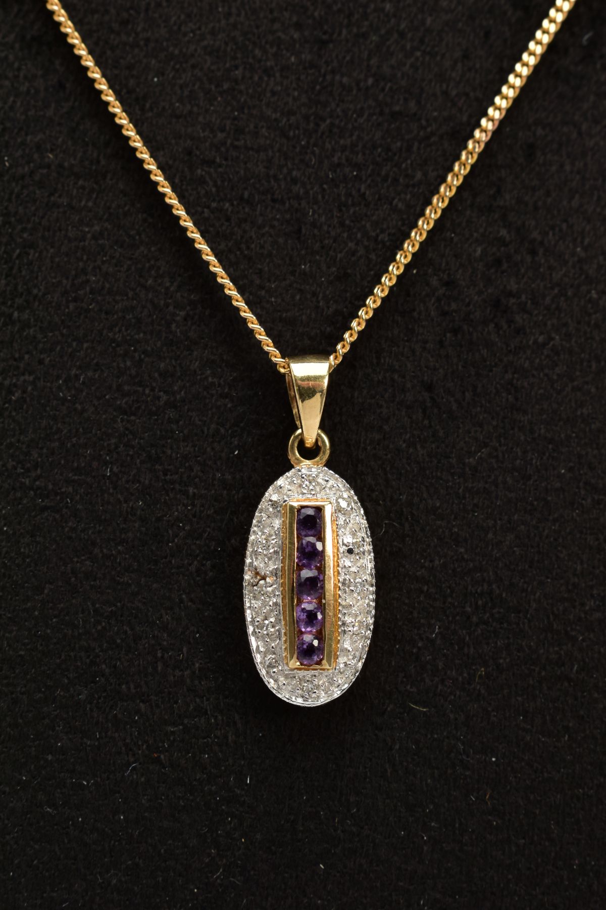 A 9CT GOLD AMETHYST AND DIAMOND PENDANT NECKLACE, the oval pendant designed with a central row of