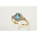 A 9CT GOLD BLUE TOPAZ AND DIAMOND CLUSTER RING, designed with an oval cut blue topaz within a