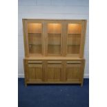 A MARKS AND SPENCERS SOLID OAK GLAZED TRIPLE DOOR BOOKCASE, with internal lighting and glass