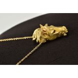 A MODERN HORSE HEAD PENDANT, realistically stylized, textured finish with ruby eyes, pendant