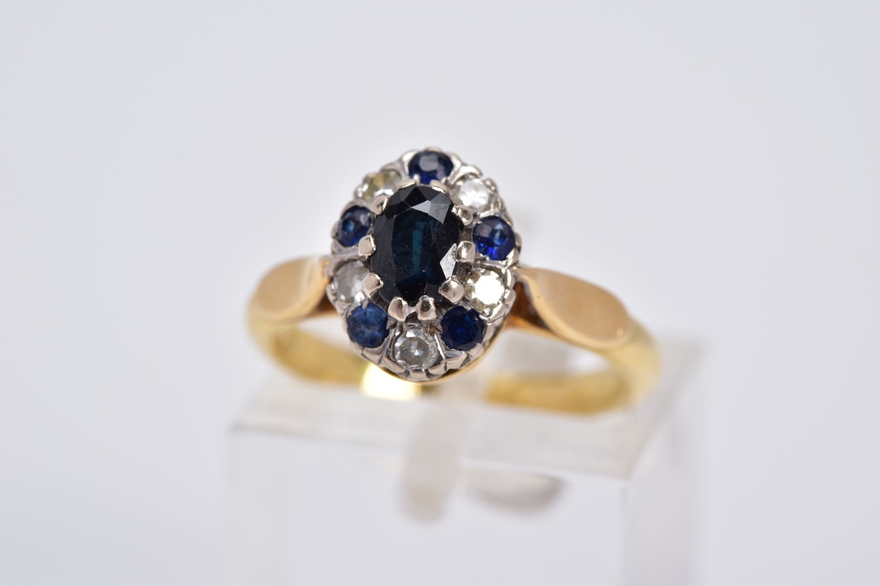 A SAPPHIRE AND DIAMOND CLUSTER RING, of tiered design set with a central oval cut sapphire, within a