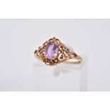 A 9CT GOLD AMETHYST RING, designed with a claw set, oval cut amethyst, within an openwork scroll