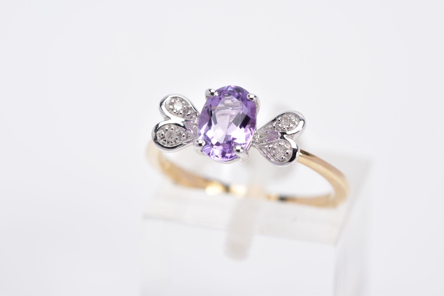 A 9CT GOLD AMETHYST AND DIAMOND RING, designed with a claw set, oval cut amethyst, with heart shaped