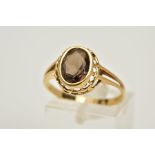 A 9CT GOLD SMOKEY QUARTZ RING, designed with an oval cut smokey quartz within a collet mount,