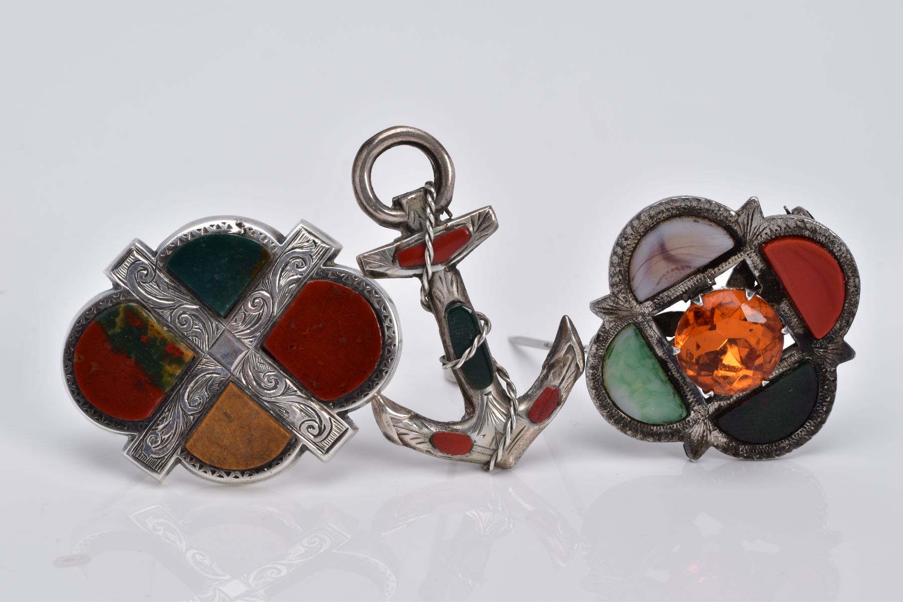 THREE SCOTTISH HARDSTONE BROOCHES, the first designed with a central circular cut orange stone