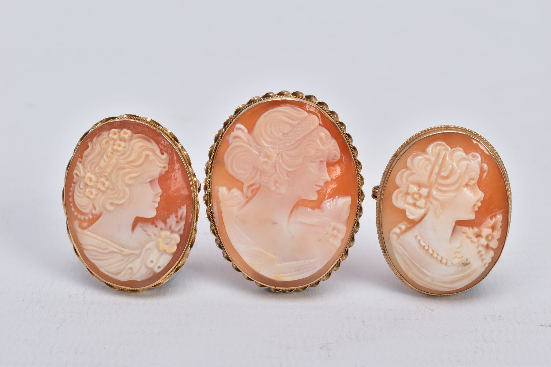 THREE 9CT GOLD CAMEO SHELL BROOCHES, each designed with women in profile within collet mounts,