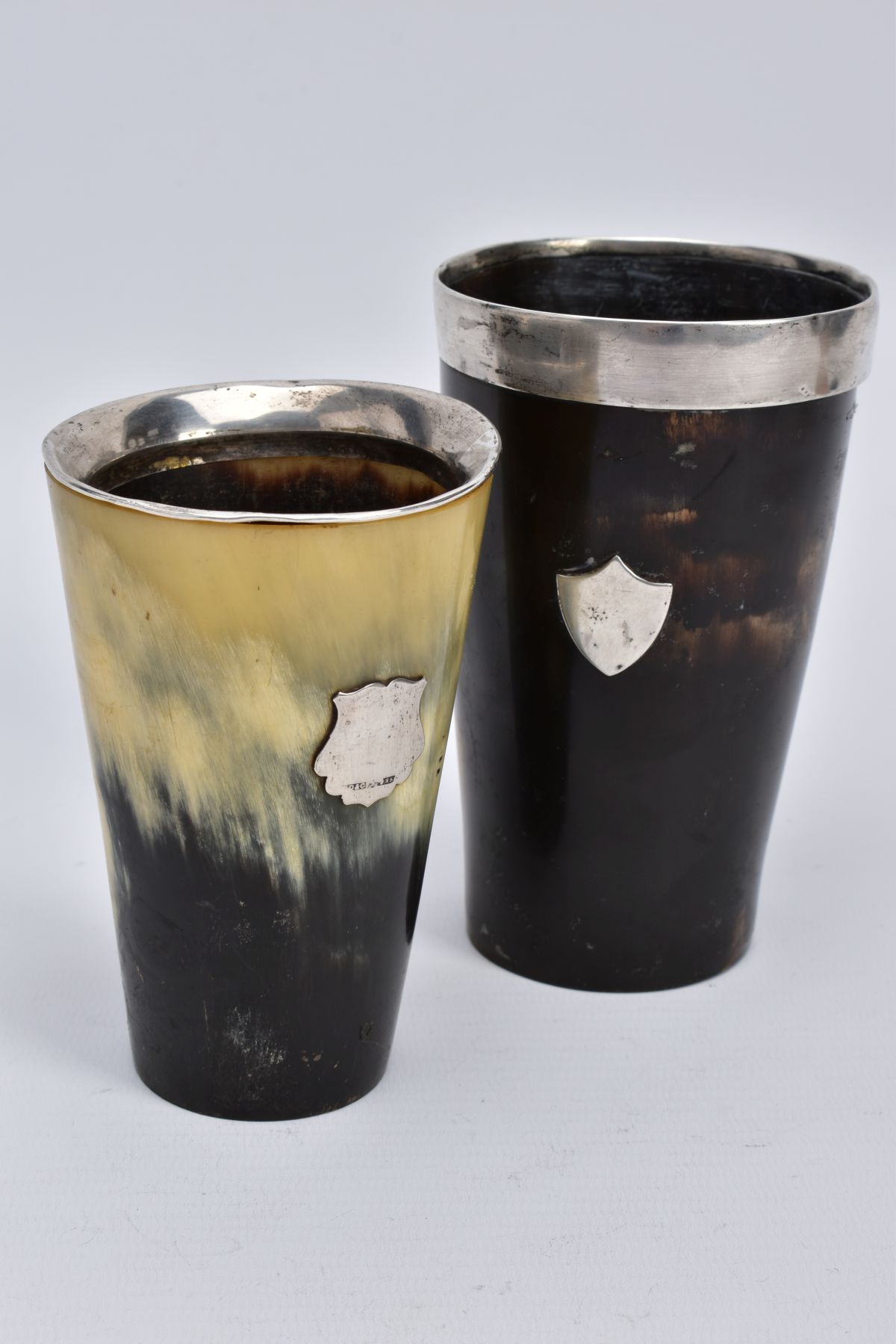 TWO HORN BEAKERS, the first of brown and cream colour, with a silver vacant cartouche to the front