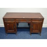 AN EDWARDIAN MAHOGANY KNEE HOLE DESK, with three various drawers above panelled cupboard doors, on