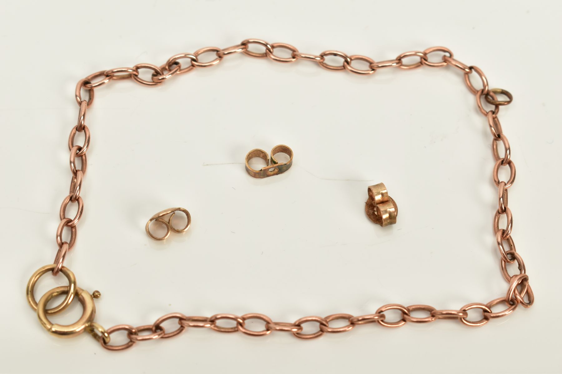 A ROSE COLOURED METAL BRACELET AND SCROLLS, the bracelet of curb link design, fitted to a spring