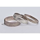 THREE SILVER HINGED BANGLES, the first a wide bangle with a foliate engrave design, push pin clasp