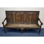 A DISTRESSED GEORGIAN OAK HALL SETTLE, having four fielded panels, swept armrests, on triple