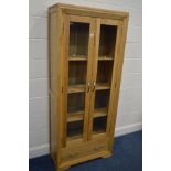 A MODERN SOLID LIGHT OAK GLAZED DOUBLE DOOR BOOKCASE, with three adjustable shelves, above a