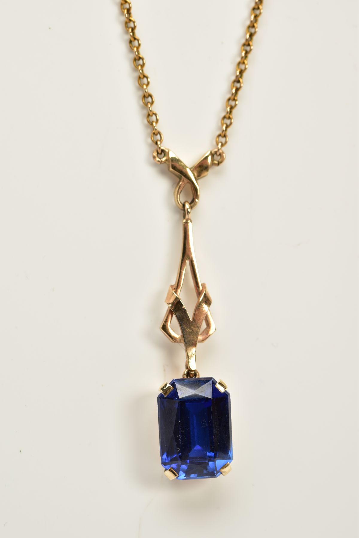 A YELLOW METAL SAPPHIRE PENDANT NECKLACE, designed with an openwork drop detailed pendant with a