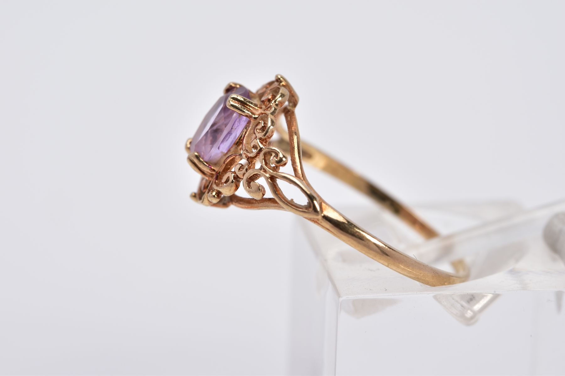 A 9CT GOLD AMETHYST RING, designed with a claw set, oval cut amethyst, within an openwork scroll - Image 2 of 3