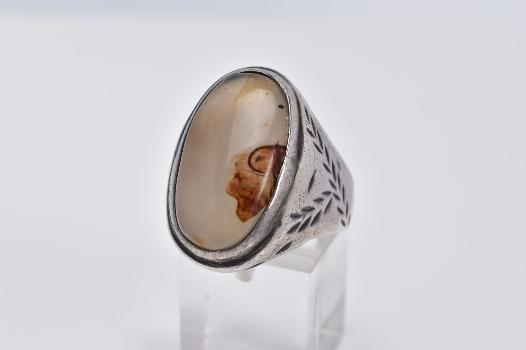 A WHITE METAL GEM SET RING, of oval design set with a cabochon cloudy stone assessed as agate,