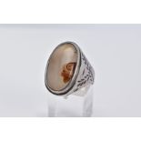 A WHITE METAL GEM SET RING, of oval design set with a cabochon cloudy stone assessed as agate,