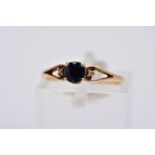 A SAPPHIRE AND DIAMOND RING, the yellow metal ring designed with a single circular cut sapphire,