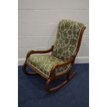 A VICTORIAN WALNUT FRAMED ROCKING CHAIR with swept open armrest and green upholstery