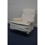 AN EDWARDIAN WHITE UPHOLSTERED ARMCHAIR on turned mahogany front legs and ceramic casters